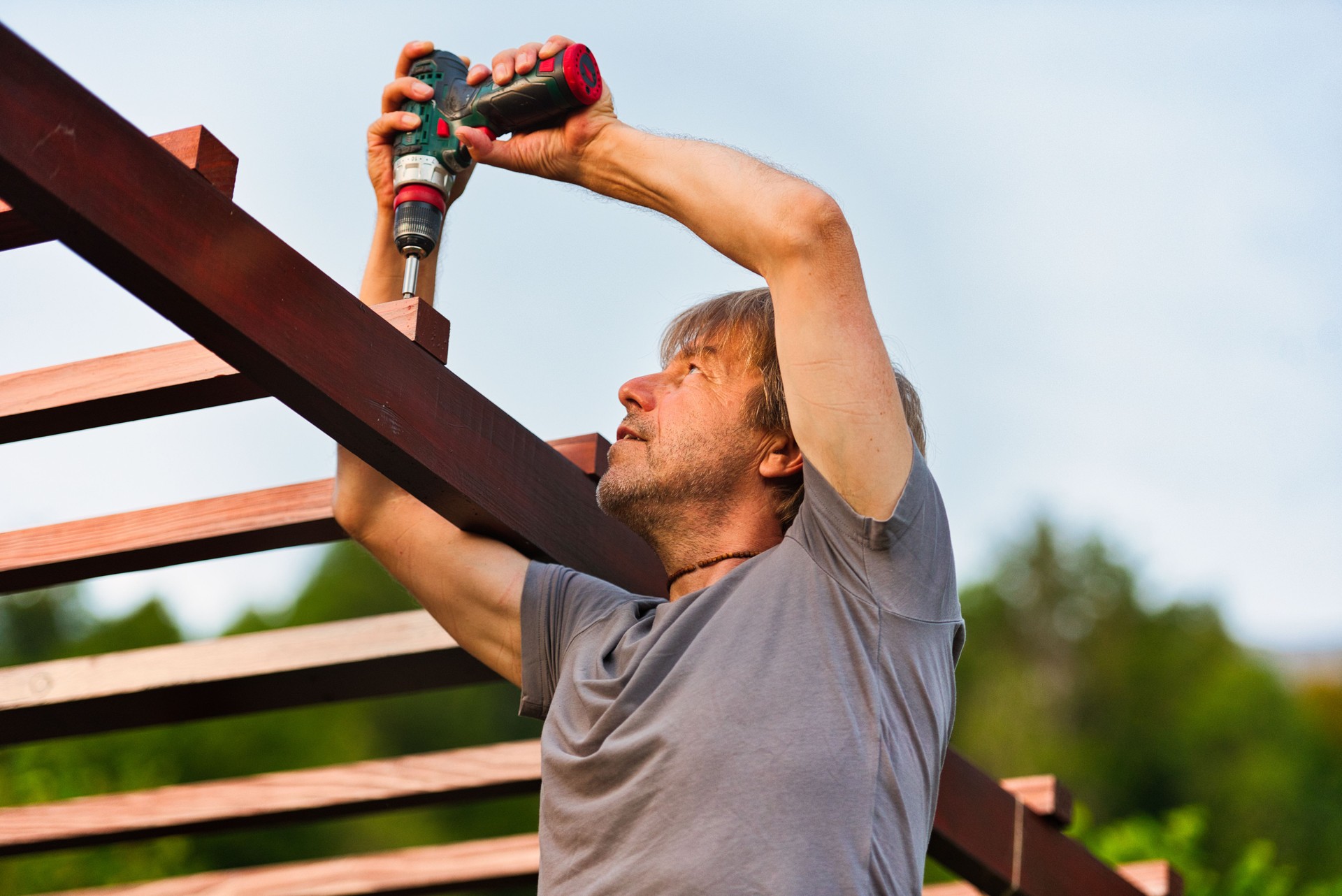 Mature Man Fixing the Wooden Backyard Pergola